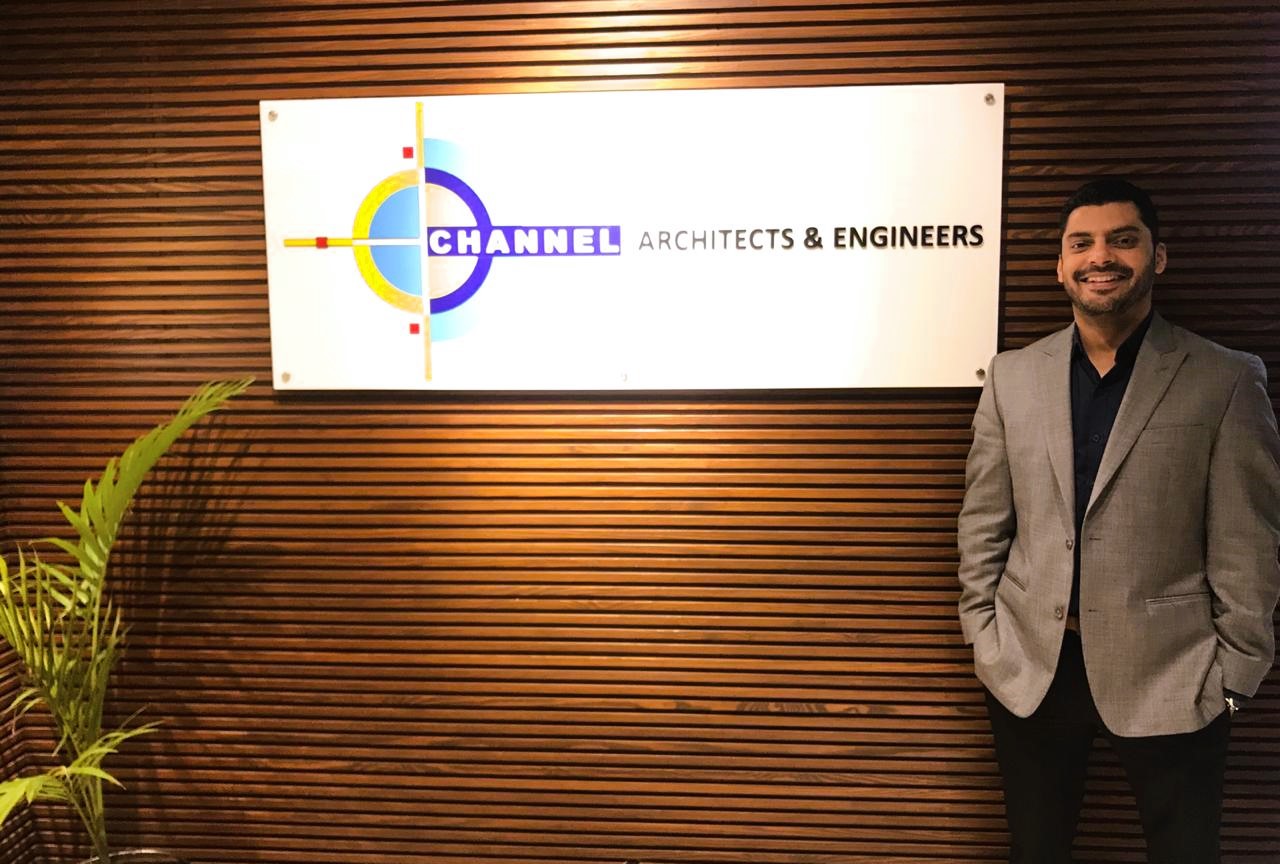 Amir Khalid, CFO of Channel Architects & Engineers, poses next to the firm's earlier logo, recalling the path of progress and ingenuity.